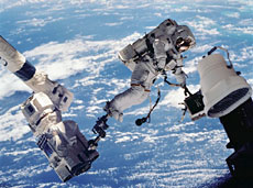 An astronaut working on the robotic arm during a spacewalk (courtesy of NASA)