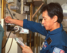 Astronaut Mamoru Mouri practicing a materials experiment inside a training version of Spacelab